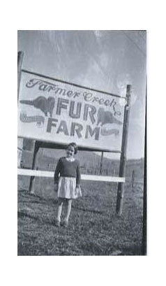 Person standing in front of a 'Farmer Creek Fur Farm' sign