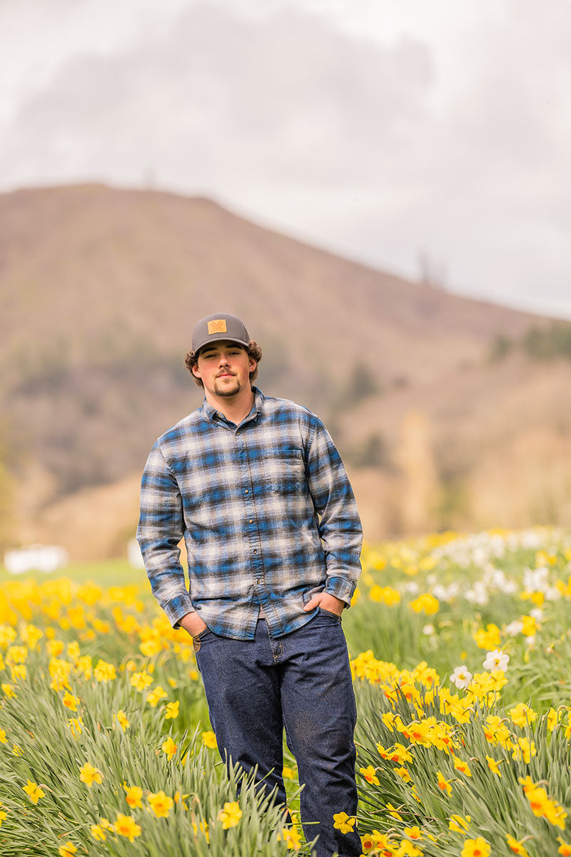 Man standing in a field of yellow flowers with mountains in the background